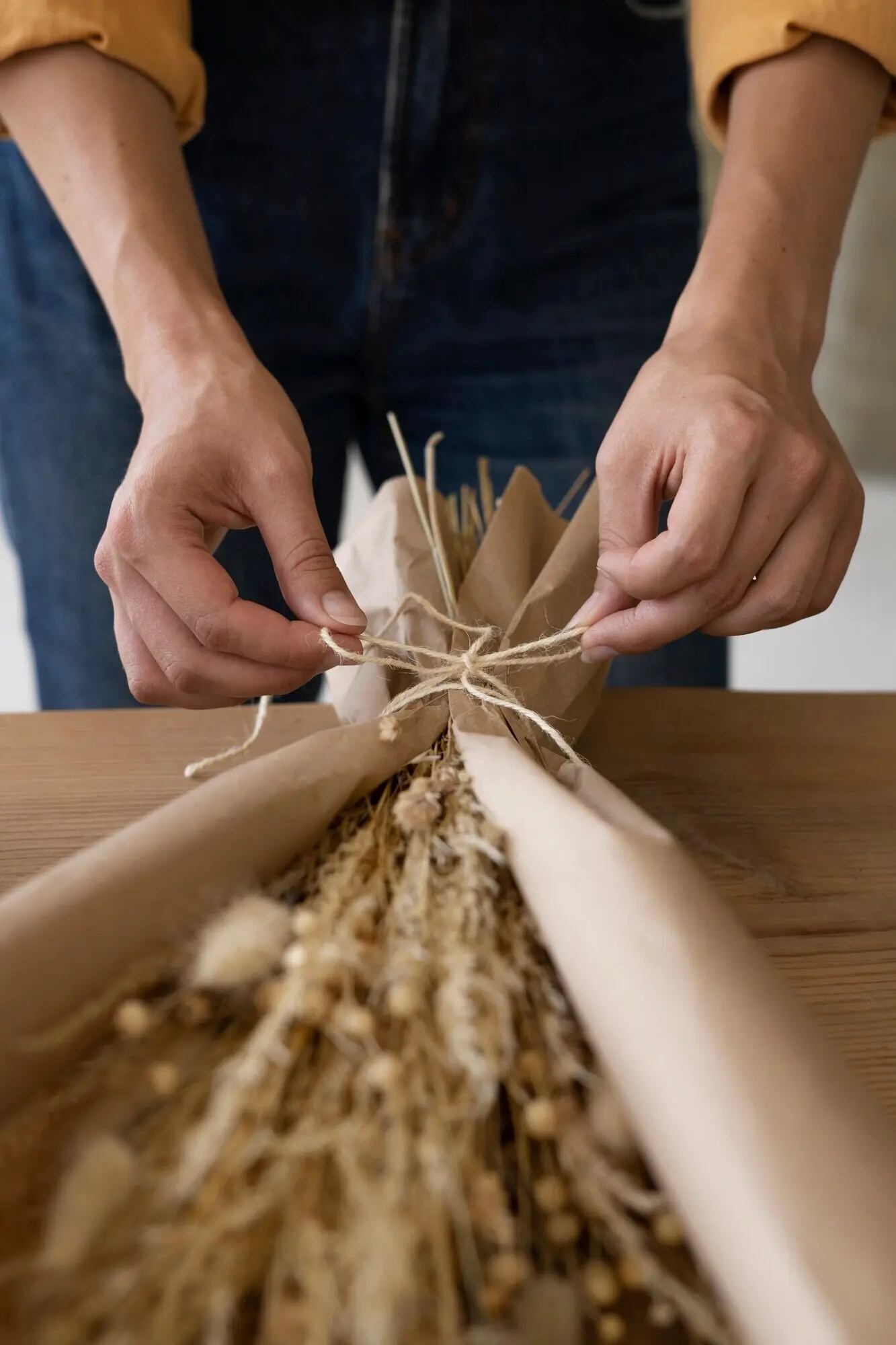 Frau, die ihr eigenes Trockenblumen-Arrangement zusammenstellt.